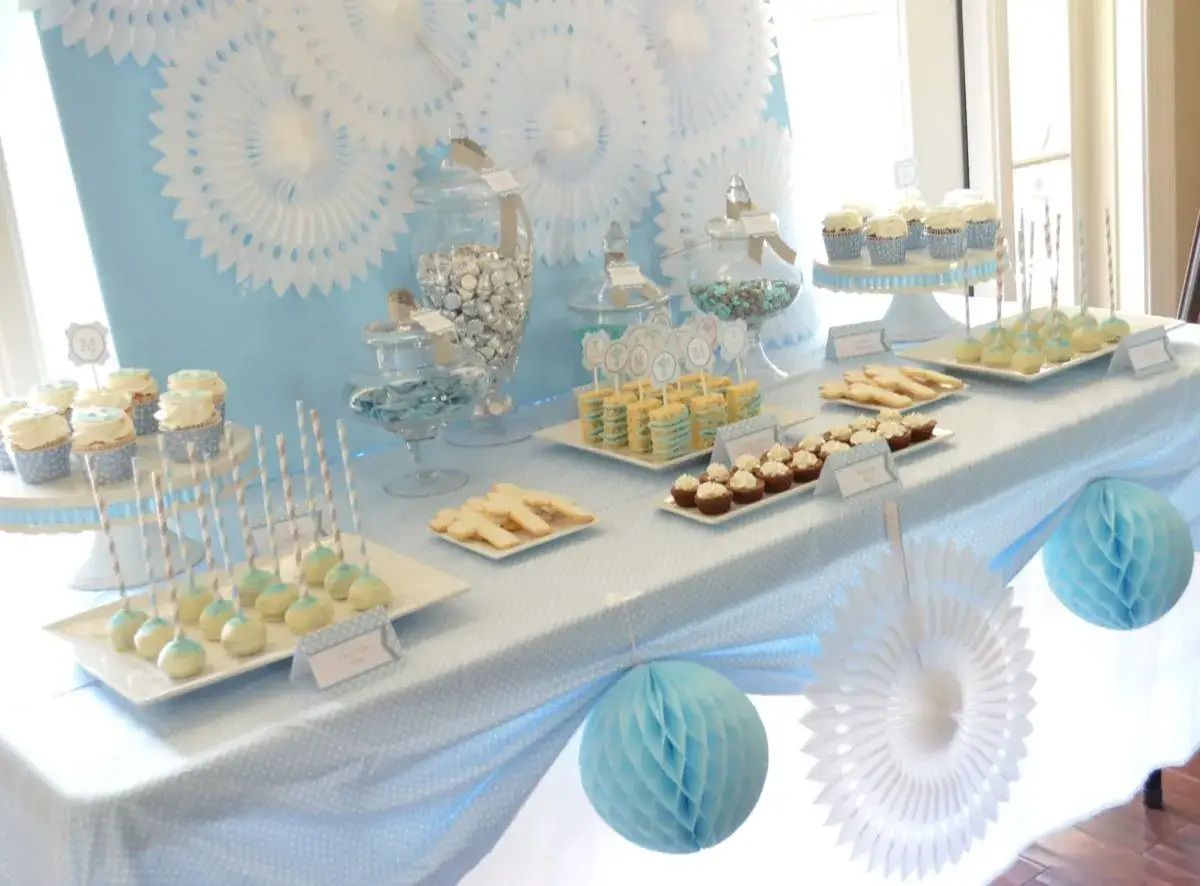 Tavola allestita per un baby shower: dolci, cupcake, biscotti e caramelle in un'atmosfera azzurra e bianca.