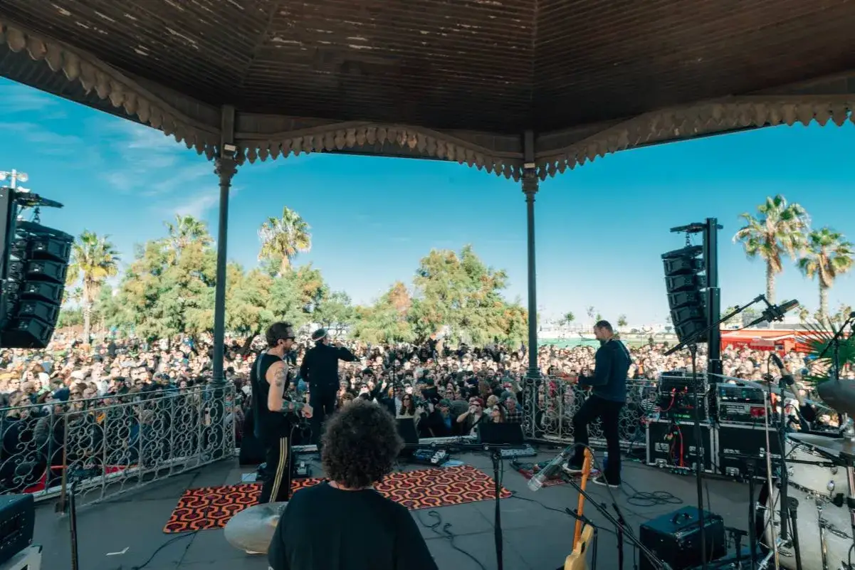 Banda tocando en un escenario al aire libre ante una multitud entusiasta. ¡Ya se vislumbran los conciertos Valencia 2026!