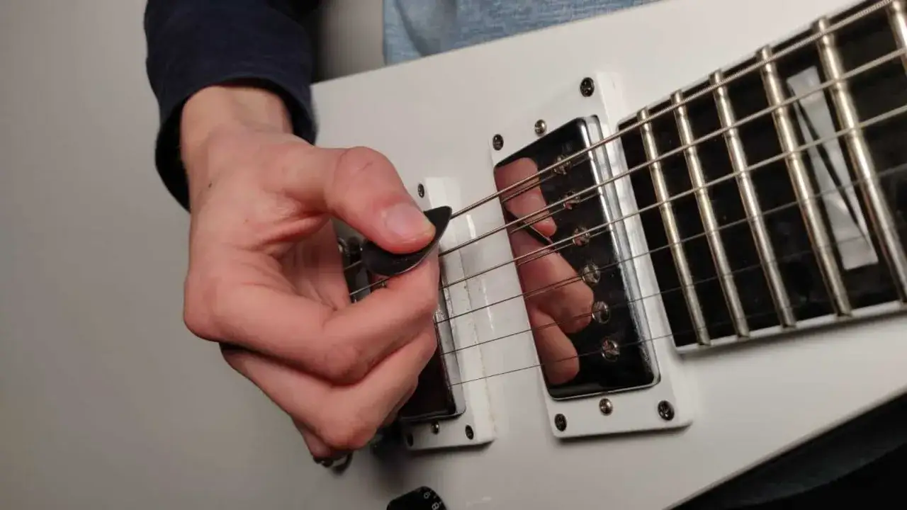 Hand spielt Gitarre, Plektrum d&auml;mpft Saiten f&uuml;r einen knackigen **palm mute** Sound.