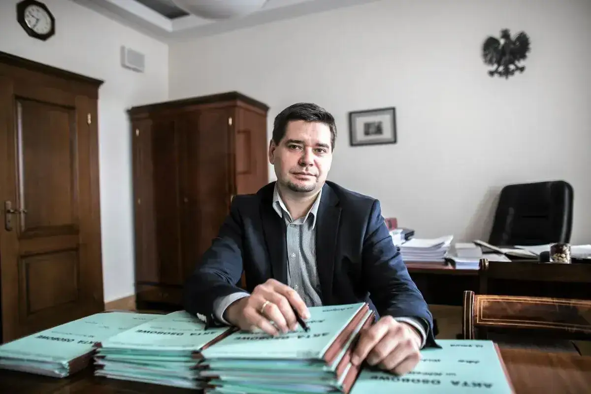 Mężczyzna w garniturze siedzi przy biurku z aktami. Czy adwokat niewykonujący zawodu może chodzić do sądu?