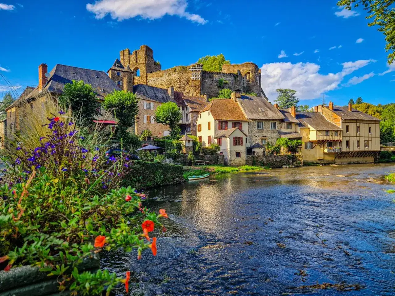 Un village pittoresque en Corr&egrave;ze, avec un ch&acirc;teau en ruines surplombant des maisons anciennes au bord d'une rivi&egrave;re. Id&eacute;al pour savoir que faire en Corr&egrave;ze.