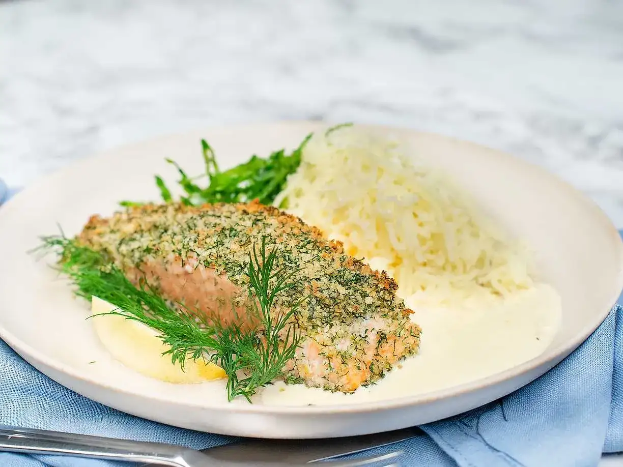 En panerad laxfil&eacute; med dill och citron serveras med ris och en kr&auml;mig citrons&aring;s.