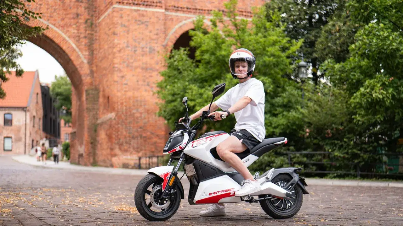 Młody mężczyzna na skuterze elektrycznym. Czy z prawem jazdy AM można wozić pasażera?