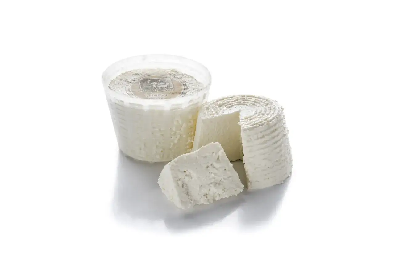 Ricotta vaccina fresca in confezione e a forma di cono, con una fetta tagliata.