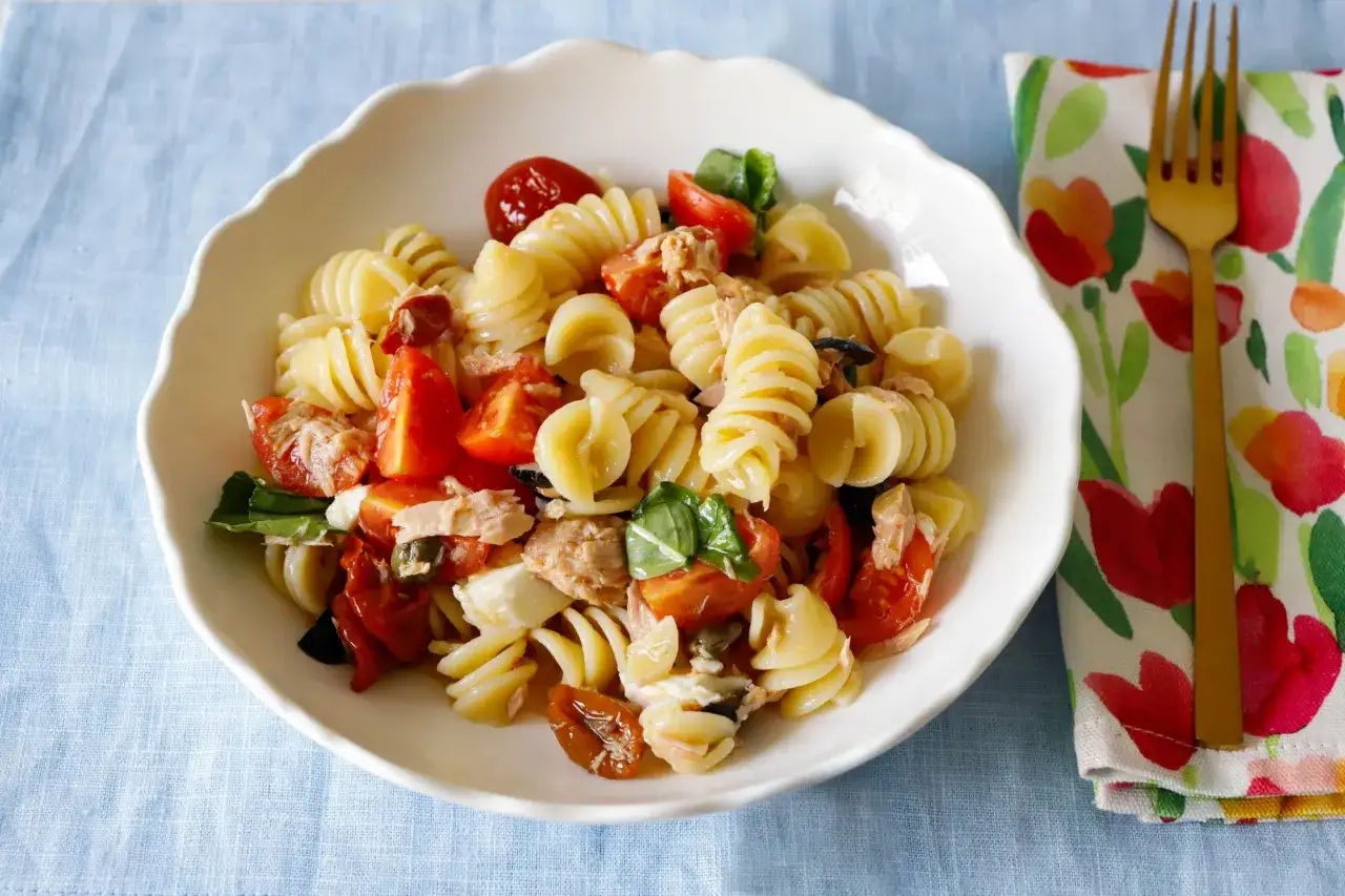 Un piatto di pasta fredda tonno con pomodorini, basilico e olive. Perfetta per un pranzo estivo.