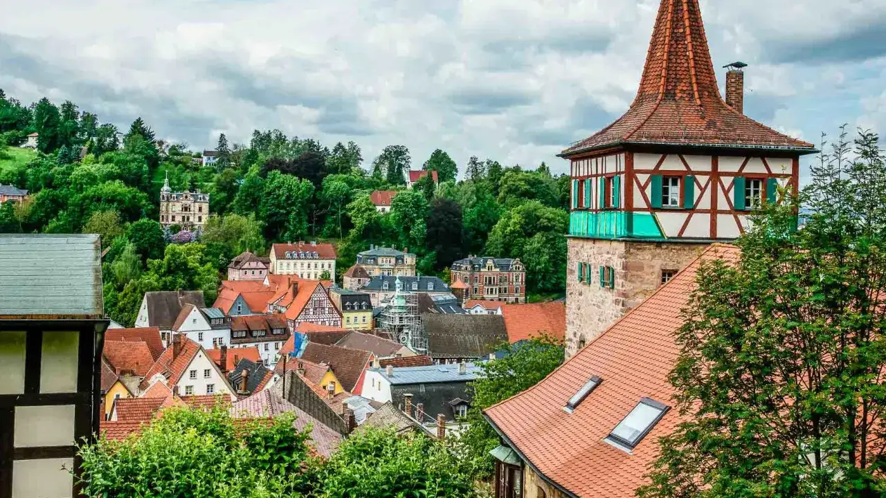 Fachwerkhäuser und ein Turm prägen das Bild der Stadt Kulmbach, die malerisch in die hügelige Landschaft von Bayreuth eingebettet ist.