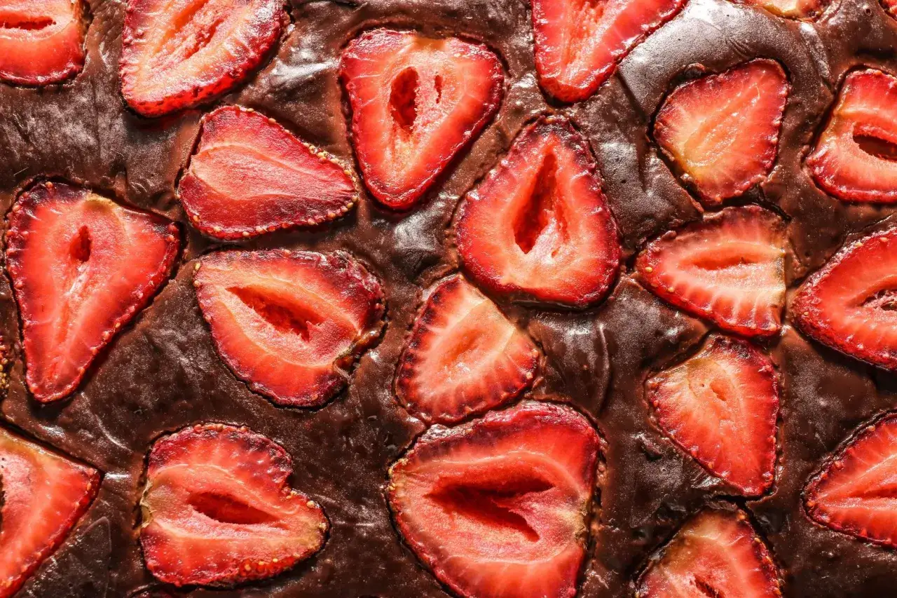 Pyszny brownie z truskawkami, z kawałkami owoców zatopionymi w czekoladowym cieście.