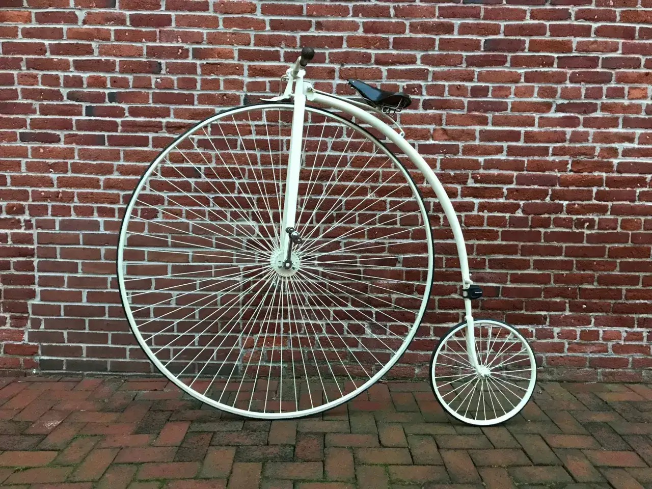 Ein Hochrad vor einer Ziegelwand. Dieses Fahrrad repr&auml;sentiert die fr&uuml;he Entwicklung des Fahrrads, mit seinem riesigen Vorderrad und dem kleinen Hinterrad.