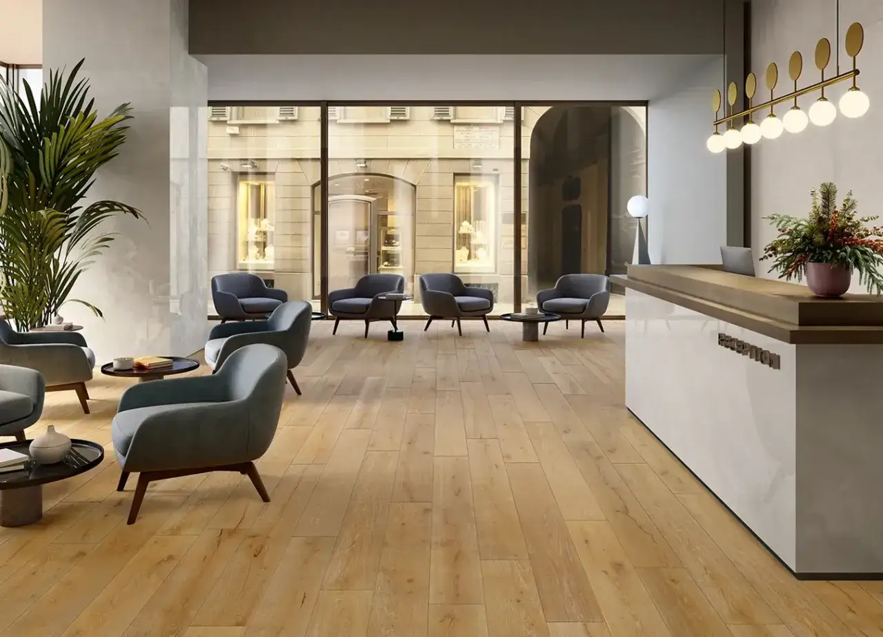 Un hall d'accueil moderne avec des fauteuils gris, une r&eacute;ception et un sol en carrelage imitation bois. L'&eacute;paisseur du carrelage sol est discr&egrave;te, soulignant l'&eacute;l&eacute;gance.