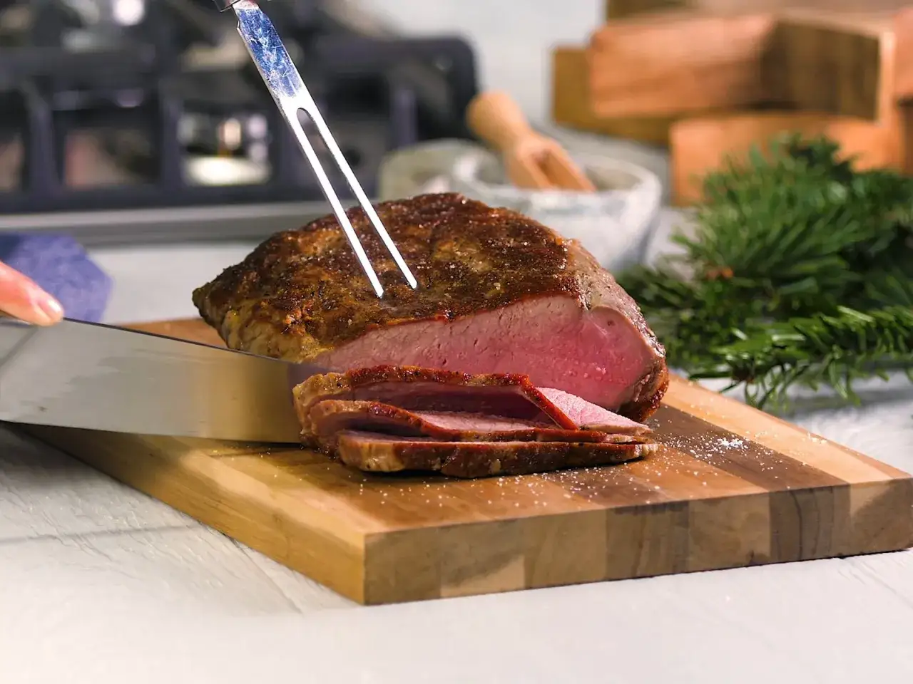 Ein saftiges Roastbeef wird auf einem Holzbrett in Scheiben geschnitten. Perfekt f&uuml;r ein festliches Mahl.