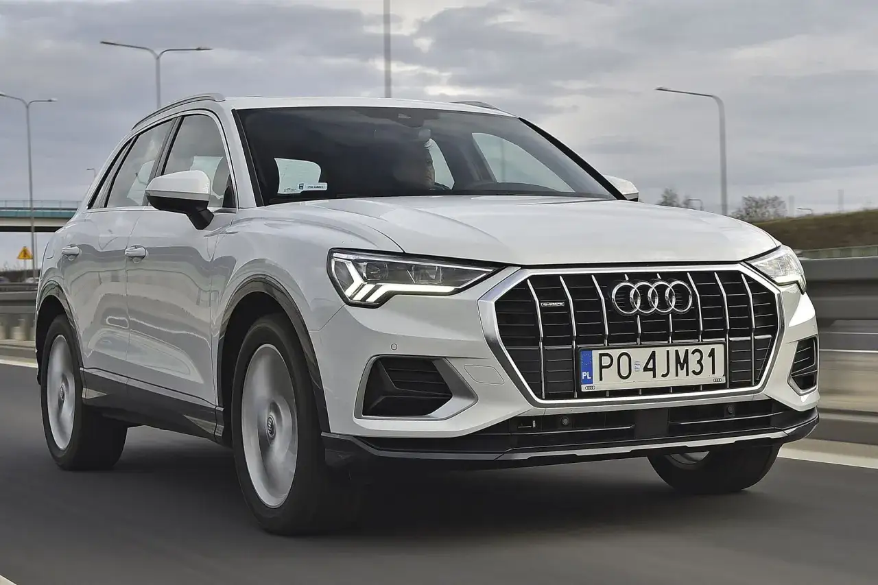Białe Audi Q3 na drodze. Sprawdź aktualną audi q3 cena i dowiedz się więcej o tym stylowym SUV-ie.