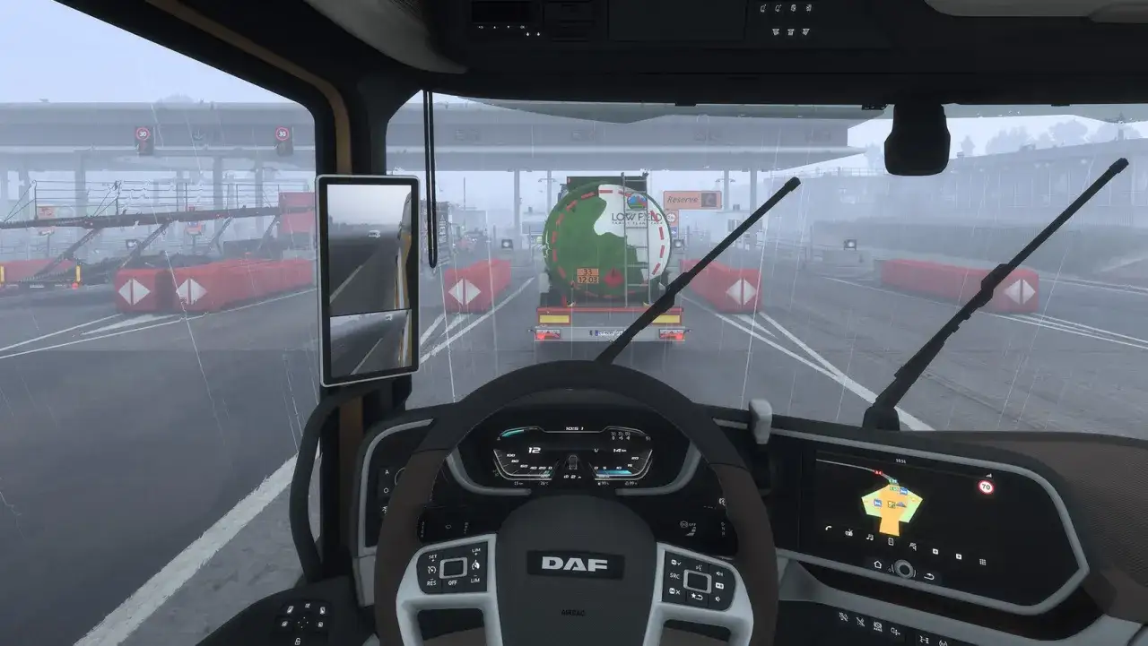 Widok z kabiny ciężar&oacute;wki w Euro Truck Simulator 2 na PS5. Deszczowa pogoda, przejazd przez bramki.