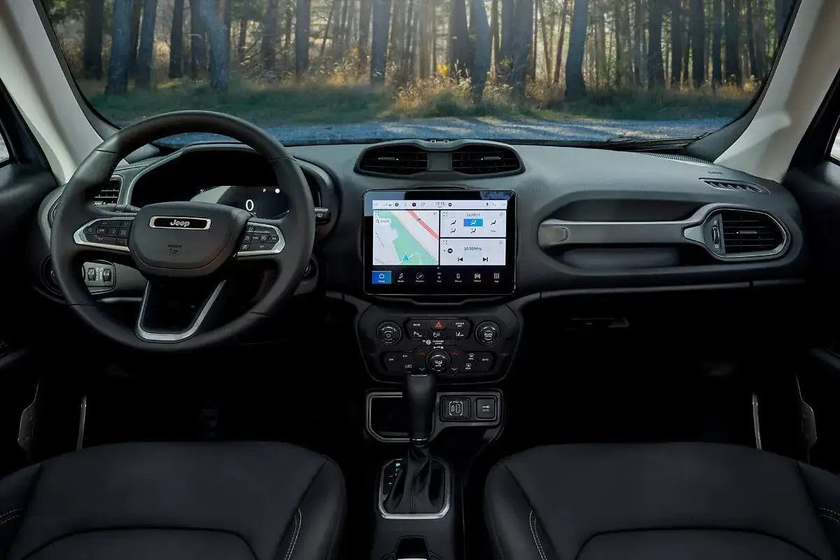 Interno della nuova Jeep Renegade 2026 con volante, schermo touchscreen e cambio automatico, pronto per l'avventura nel bosco.