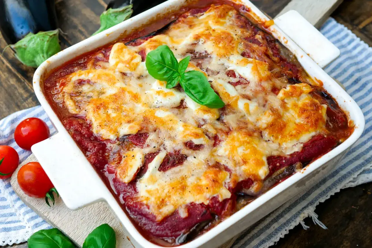 Herzhaftes Parmigiana di Melanzane Rezept: geschichtete Auberginen mit Tomatenso&szlig;e und geschmolzenem K&auml;se, garniert mit frischem Basilikum.