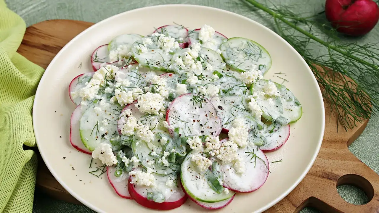 Frischer gurke radieschen salat mit cremigem Dressing und zerbröseltem Käse, garniert mit Dill.