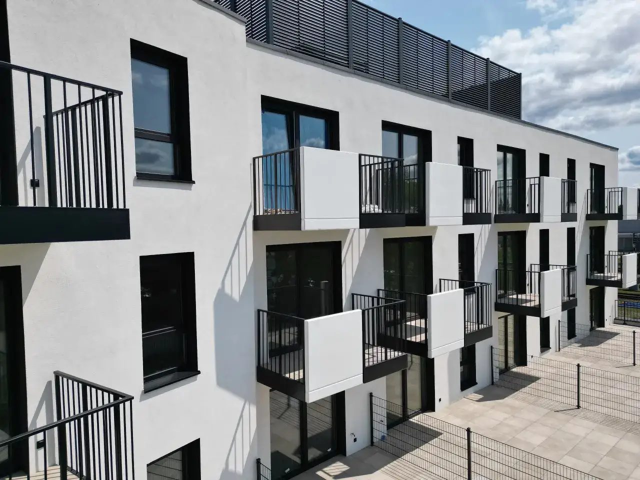 Nowoczesny budynek z balkonami i czarnymi balustradami. Majster development dba o detale.