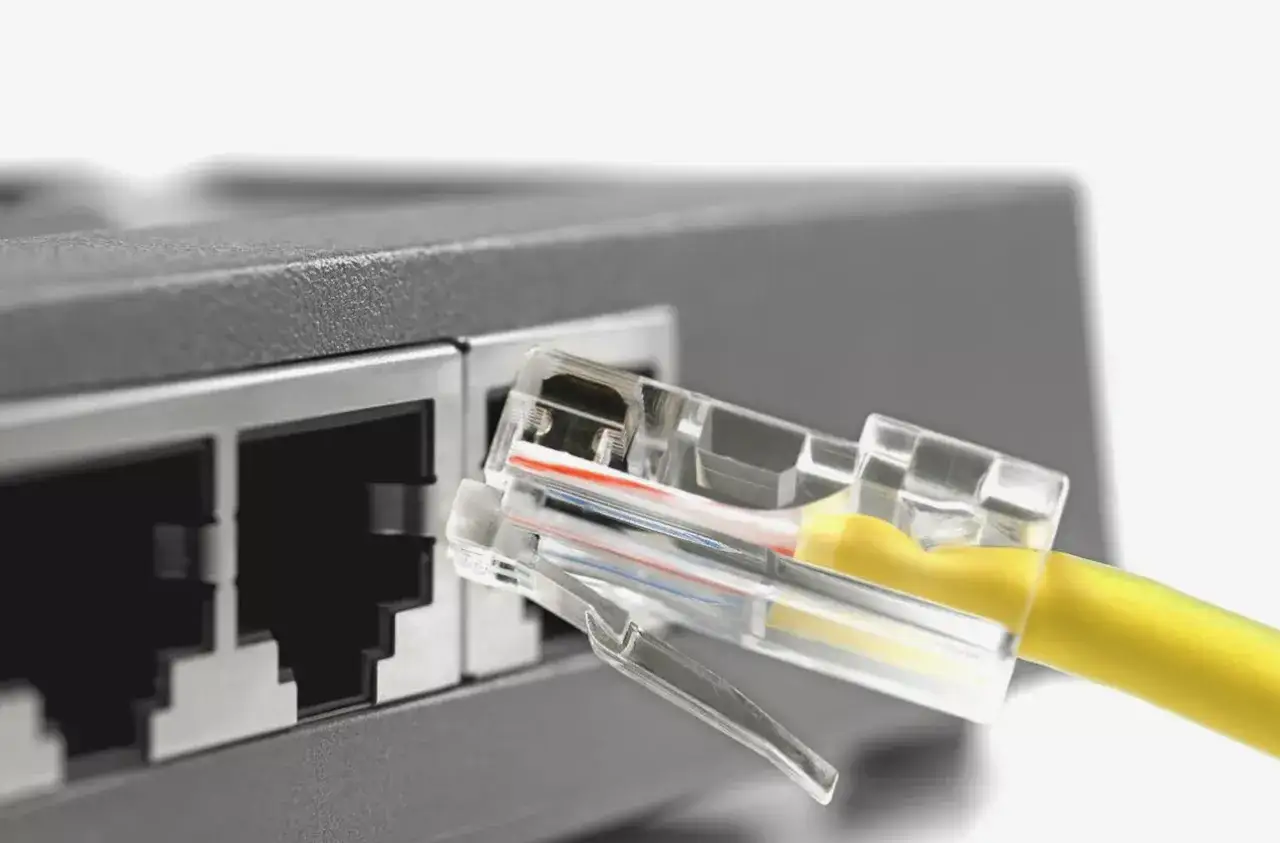 Ż&oacute;łty kabel sieciowy z przezroczystą wtyczką RJ45 gotowy do połączenia ethernet z portem routera.