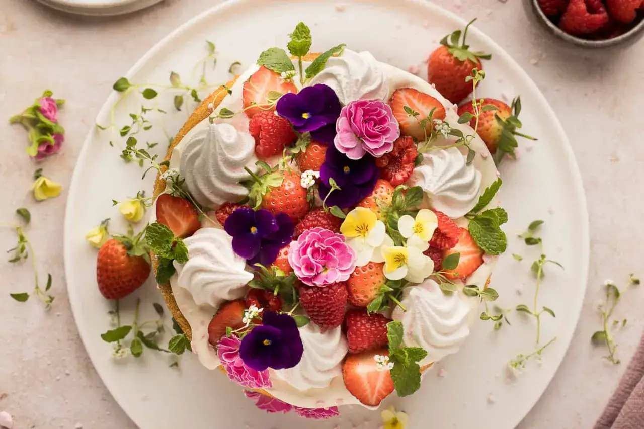 Deliciosa tarta decorada con fresas, frambuesas, merengues y flores comestibles. ¡Ideas para decorar tartas que inspiran!