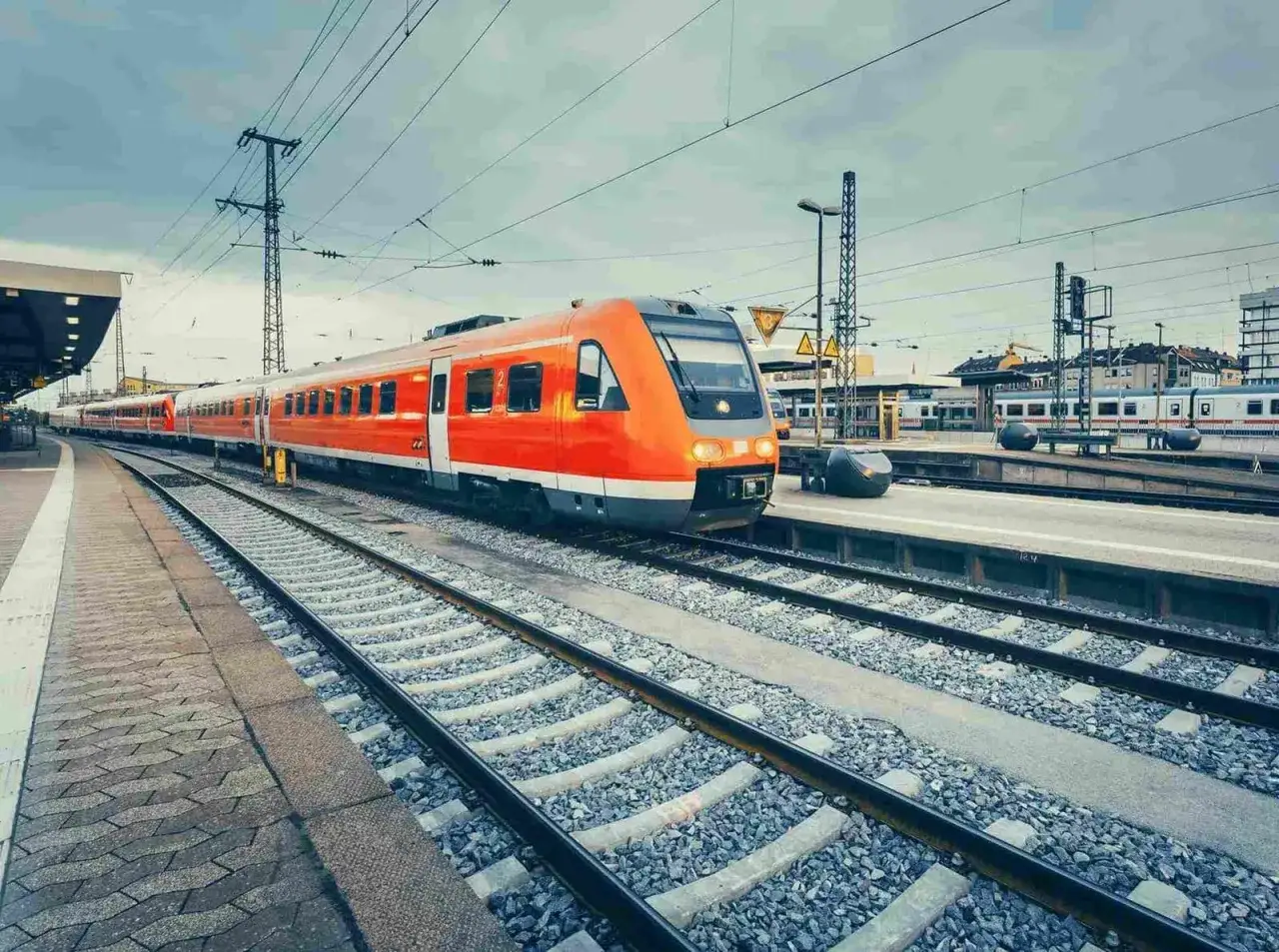 Pomarańczowy pociąg na stacji. Czy to początek podróży z Jastarni na Hel? Odległość do pokonania koleją.