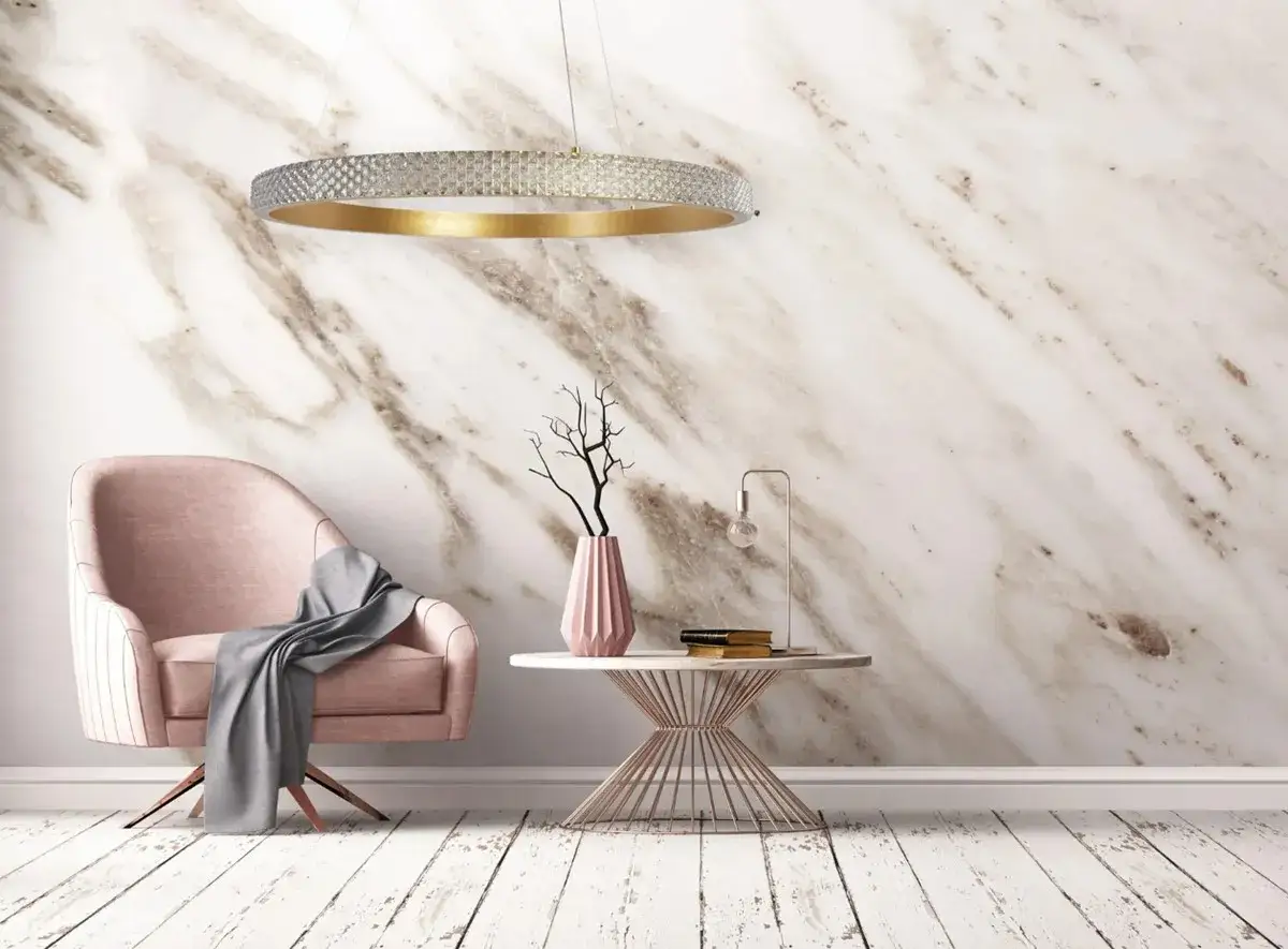 Elegancka lampa wisząca kryształowa w złotym okręgu, zawieszona nad różowym fotelem i stolikiem z wazonem.