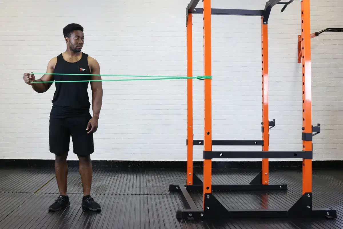 Man performing a boxing shoulder workout with a resistance band anchored to a squat rack.