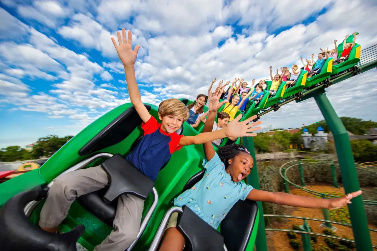 Dzieci krzyczą z radości na kolejce górskiej w **Lego Land**. Wspaniała zabawa pod błękitnym niebem!