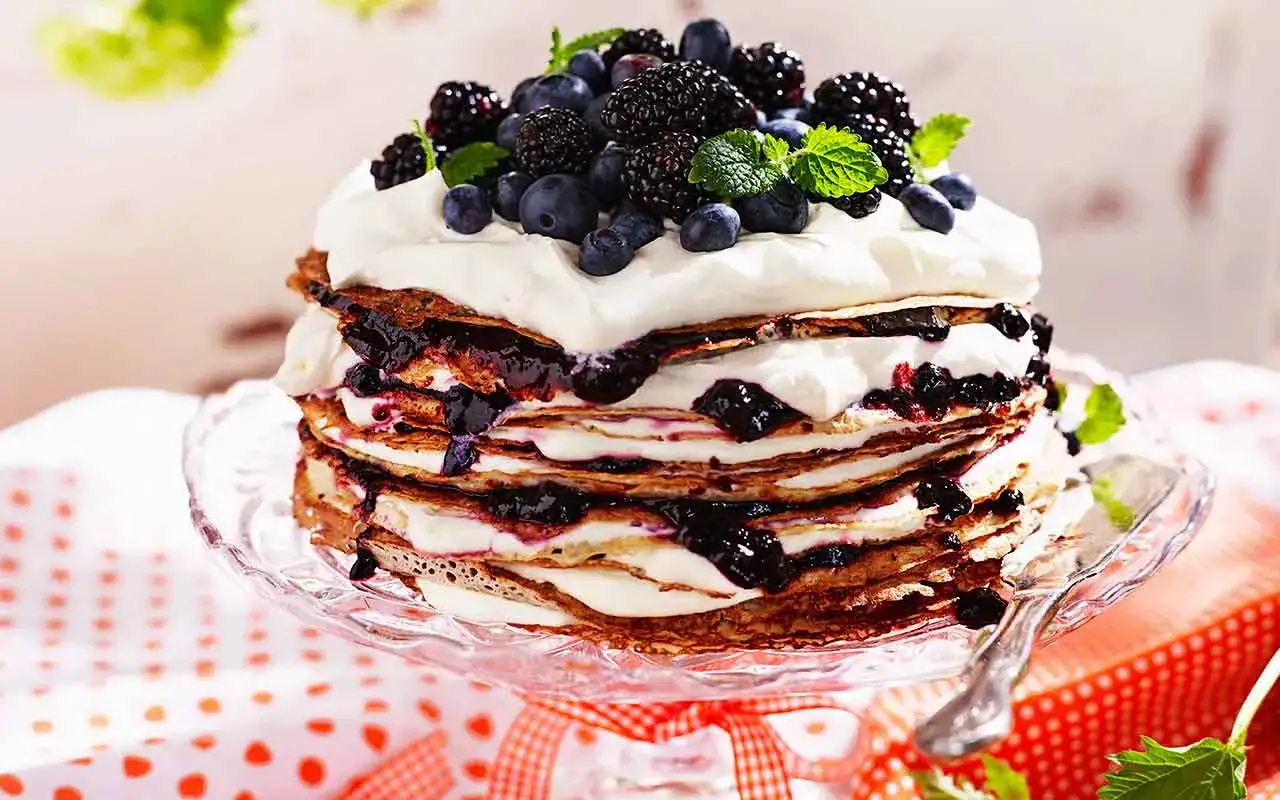 En imponerande pannkakstårta med vispgrädde och bär. Ett perfekt pannkakstårta recept för sommarens firanden.