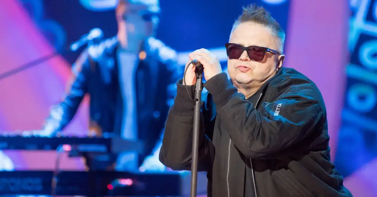 Zespół rockowy Muńka Staszczyka na scenie. Wokalista w okularach trzyma mikrofon, w tle klawiszowiec.