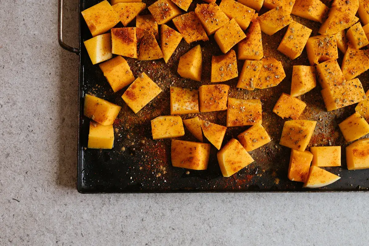 Tärnad butternutpumpa kryddad med paprika och peppar, redo för ett läckert butternutpumpa recept.