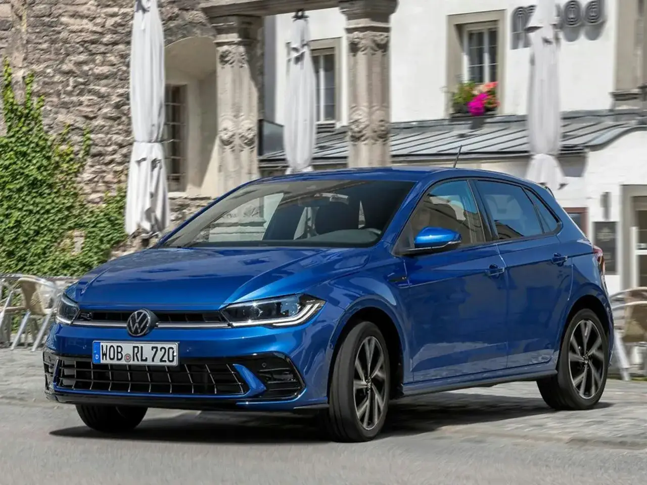 Azul VW Polo 1.0 TSI 95 CV en movimiento. ¿Problemas? Este coche parece impecable en esta calle europea.