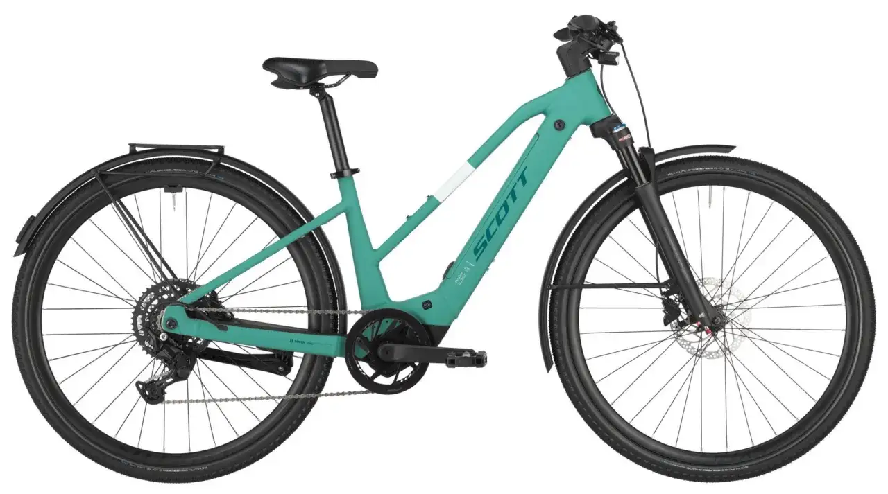Turkusowy rower elektryczny Scott z bagażnikiem i błotnikami, idealny do miejskich podróży i wycieczek. Warto go uwzględnić w rankingu rowerów elektrycznych.