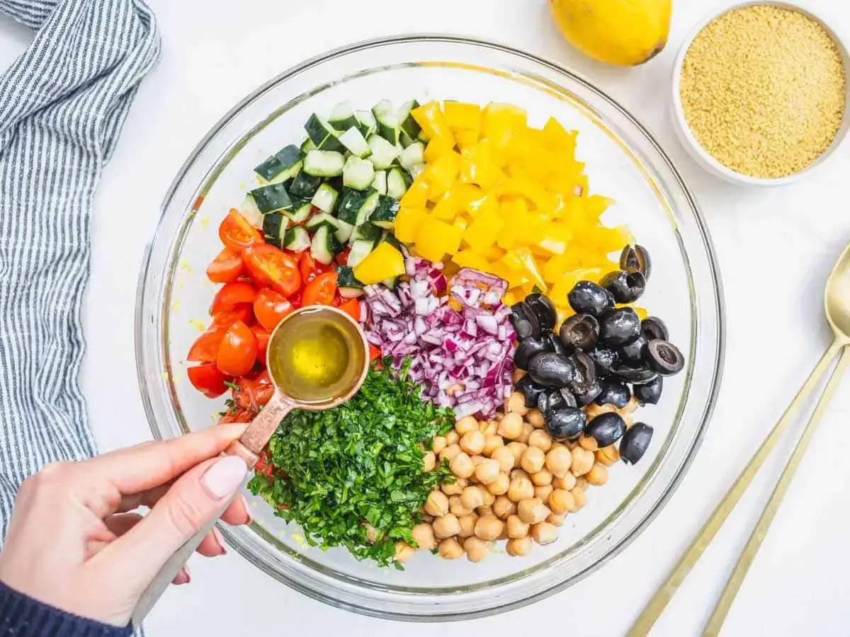 Un colorato cous cous con verdure: pomodorini, cetrioli, peperoni gialli, cipolla rossa, olive nere, ceci e prezzemolo, condito con olio.