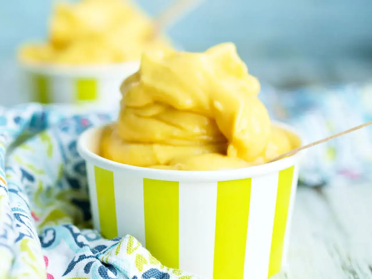 Cremiges Mango-Eis, frisch zubereitet mit der Eismaschine, serviert in bunten Bechern. Ein Genuss für heiße Tage!