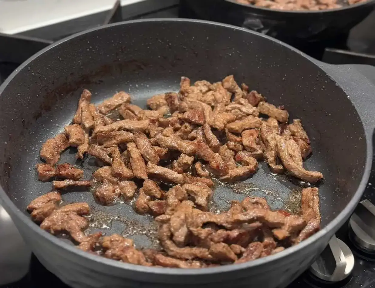 Strimlad biff steks i en panna, redo f&ouml;r ett klassiskt biff stroganoff recept.
