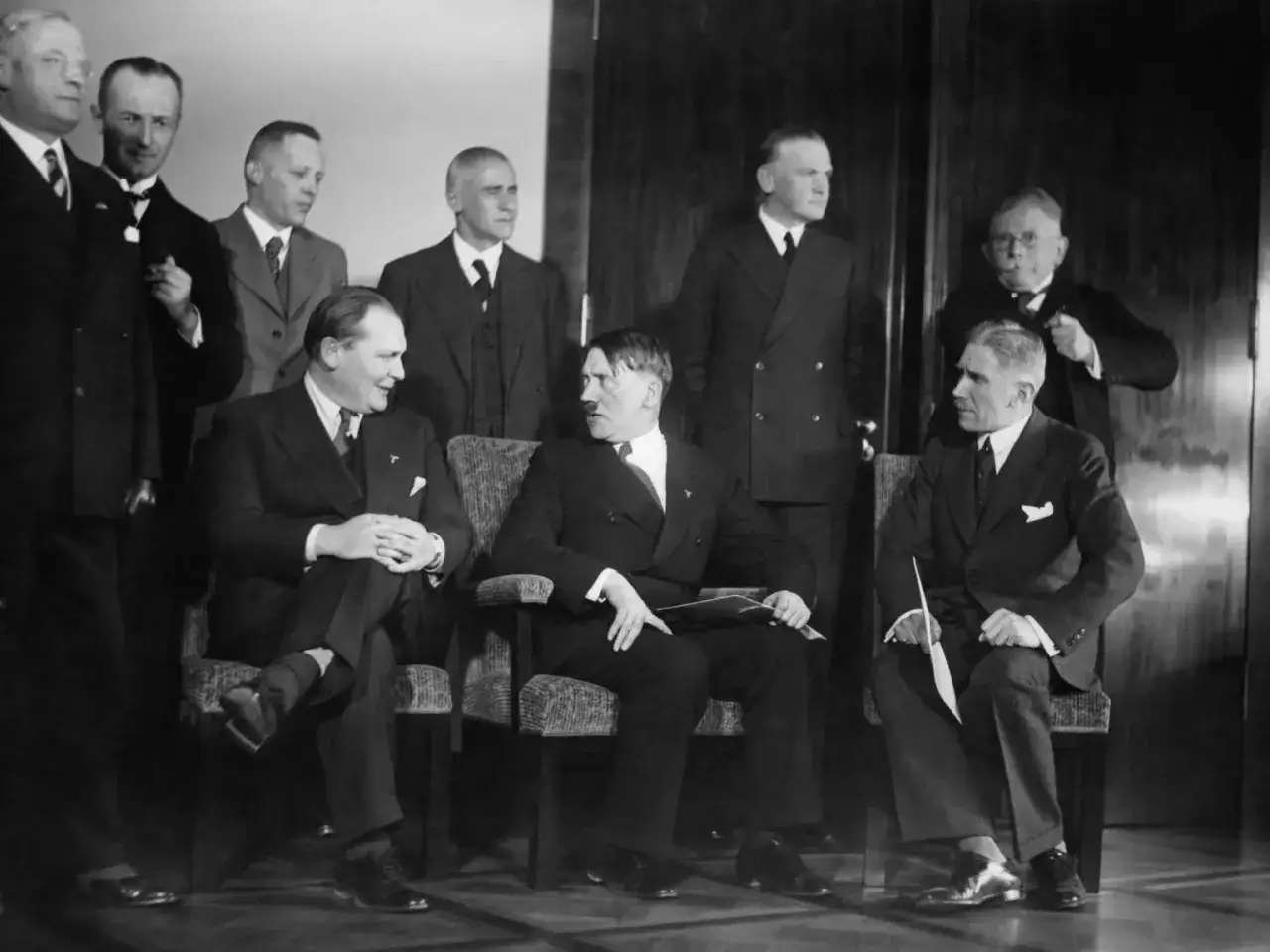 M&auml;nner in Anz&uuml;gen, darunter Hitler, sitzen und stehen. Ein Blick auf die Zeit, als Hitler an die Macht kam.