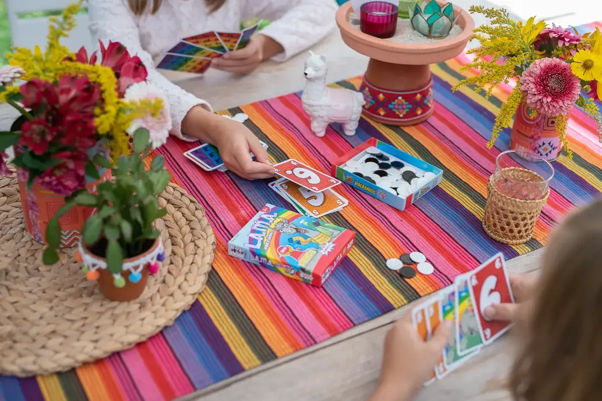 Bunte Tischdecke, Blumen und Spiele für einen kindergeburtstag kreativ. Kinder spielen Karten und Brettspiele.