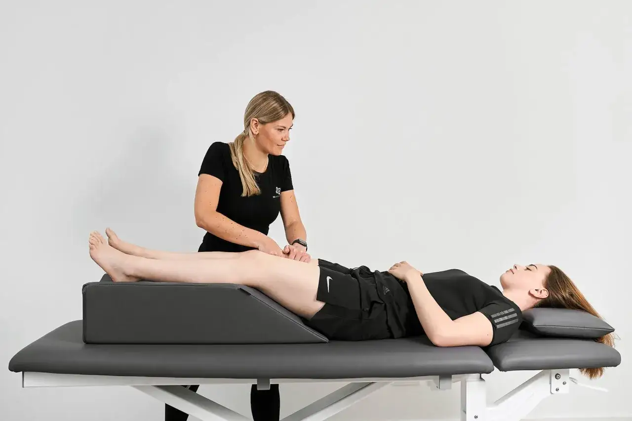 Therapeutin f&uuml;hrt eine Lymphdrainage-Massage am Bein einer liegenden Patientin durch.