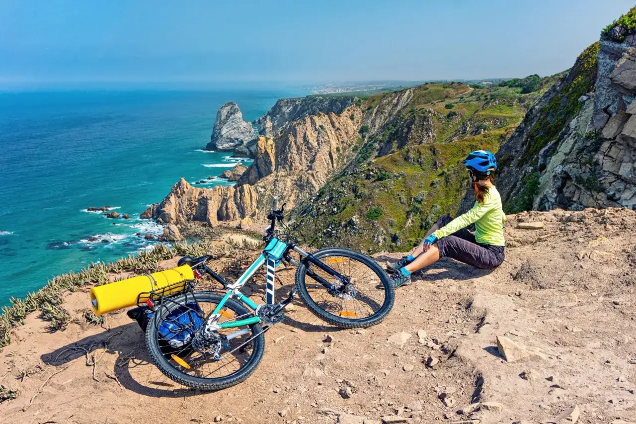 Radfahrerin mit ihrem Rennrad auf Madeira genießt die Aussicht auf die zerklüftete Küste und das türkisfarbene Meer.