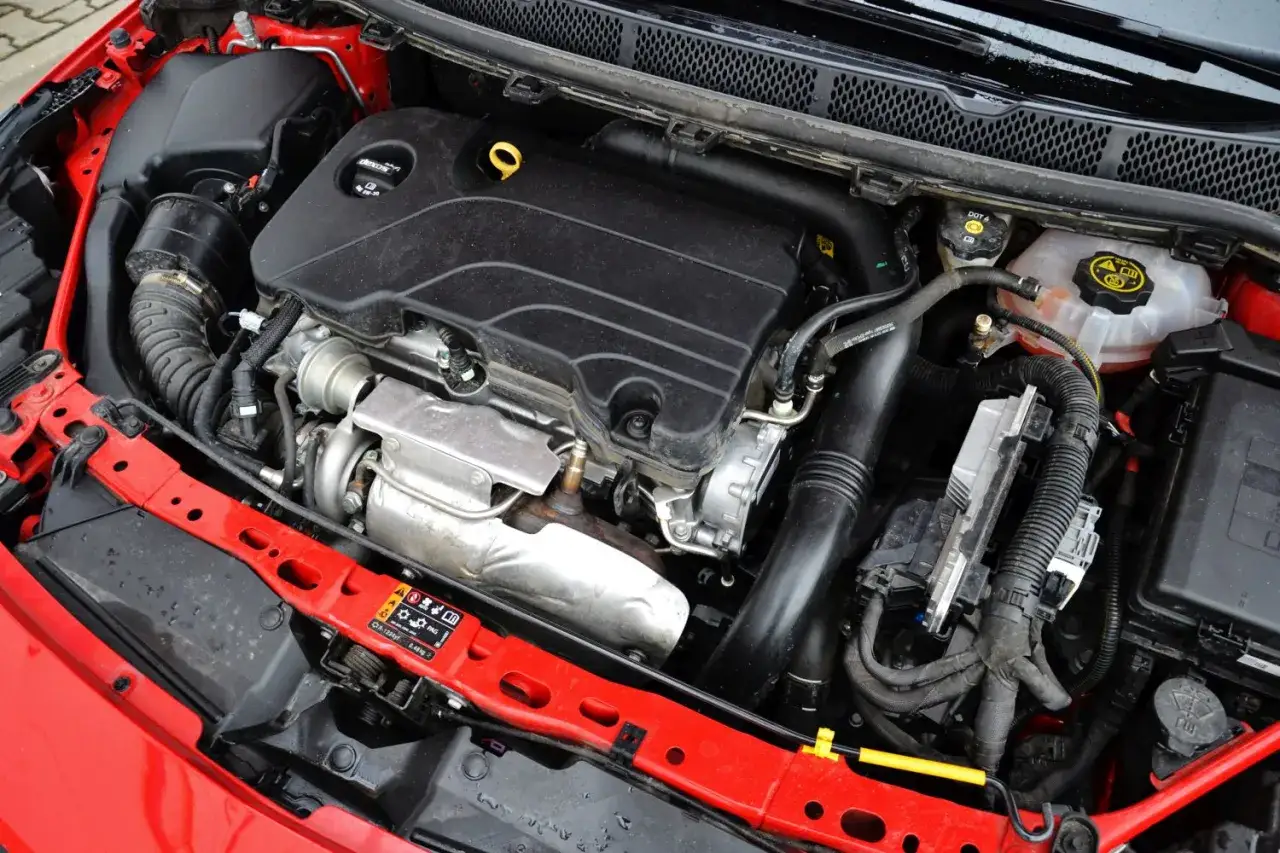Silnik Opel Astra 1.4 Turbo, czarny, z widocznym turbosprężarką i elementami układu dolotowego.