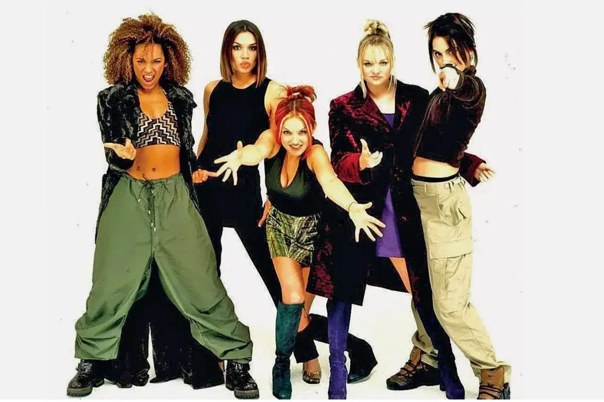 Dziewczyny z Spice Girls w stylizacjach y2k: Mel B w bojówkach, Geri w mini, Emma w fioletowej sukience, Posh w aksamicie i Sporty w dresie.