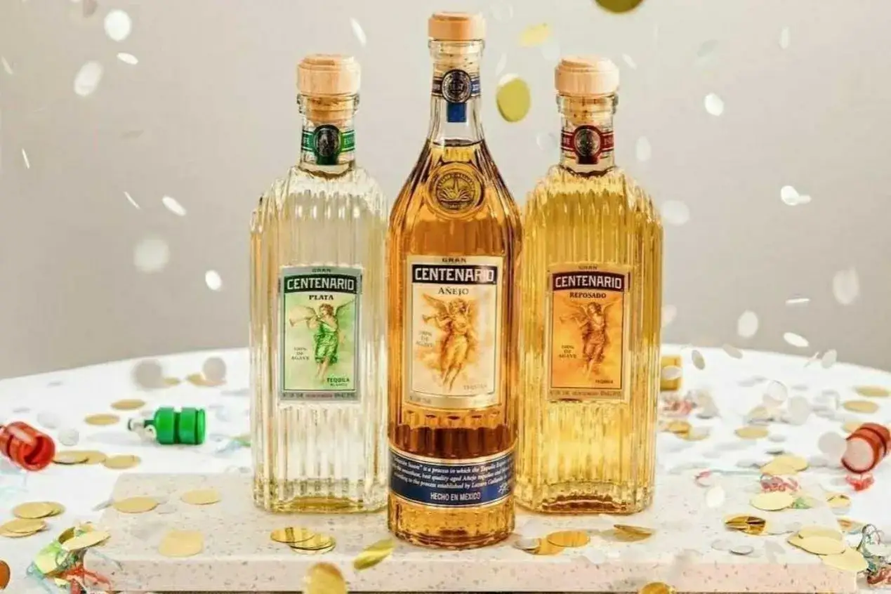 Trzy butelki tequili Gran Centenario: Plata, Añejo i Reposado, otoczone konfetti. Szukasz najlepsza tequila cena?