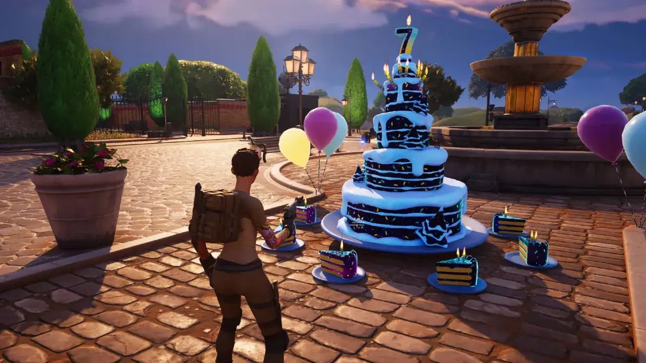 Postać w grze Fortnite świętuje urodziny. Na stole stoi tort z cyfrą 7 i zapalonymi świeczkami, a wok&oacute;ł niego porozstawiane są mniejsze kawałki ciasta.