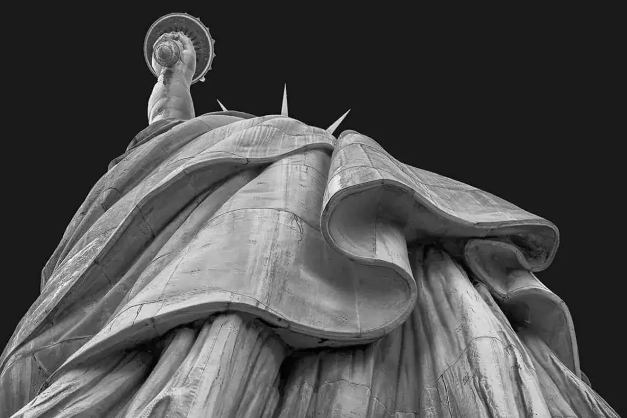 Widok z dołu na Statuę Wolności, podkreślający jej monumentalność. To świetny przykład zastosowania rodzajów perspektyw w fotografii.
