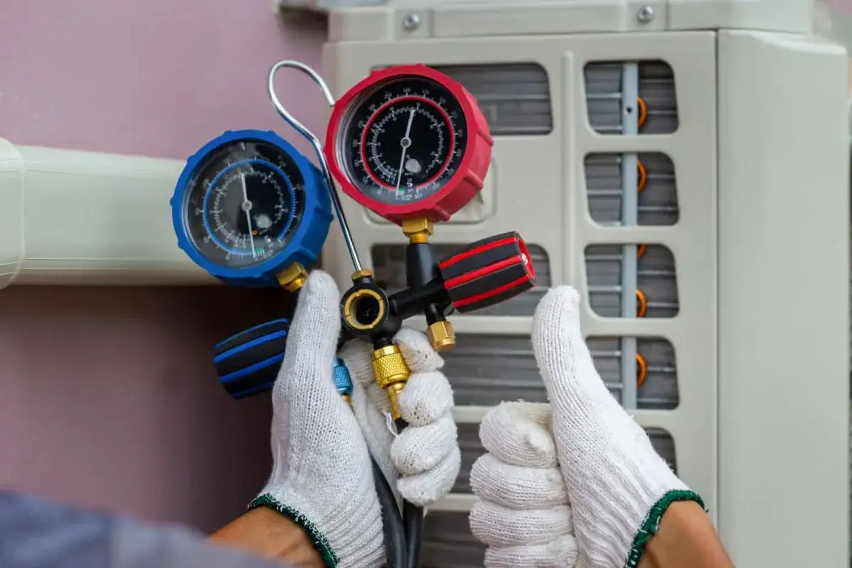 Technicien vérifiant la pression d'une pompe à chaleur avec un manomètre. Un geste pour assurer la fiabilité de l'appareil.