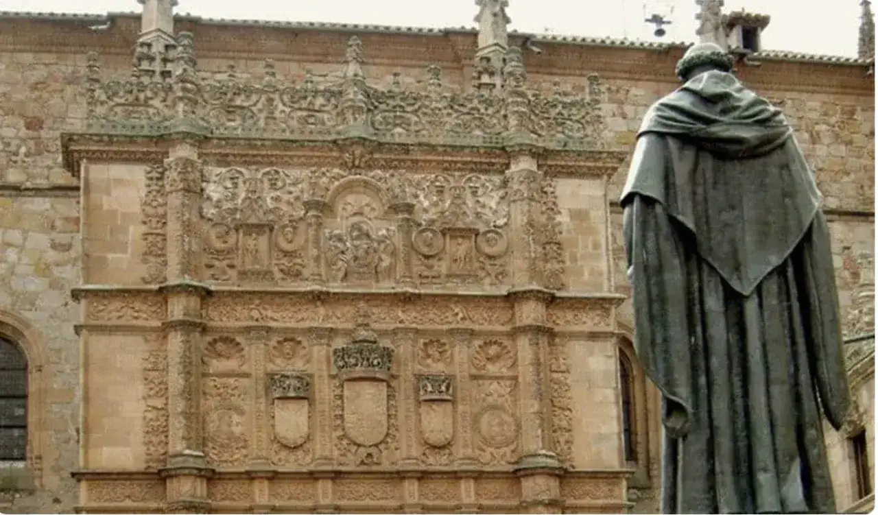 Estatua de Francisco de Vitoria frente a la fachada plateresca de la Universidad de Salamanca, con su detallada ornamentación.