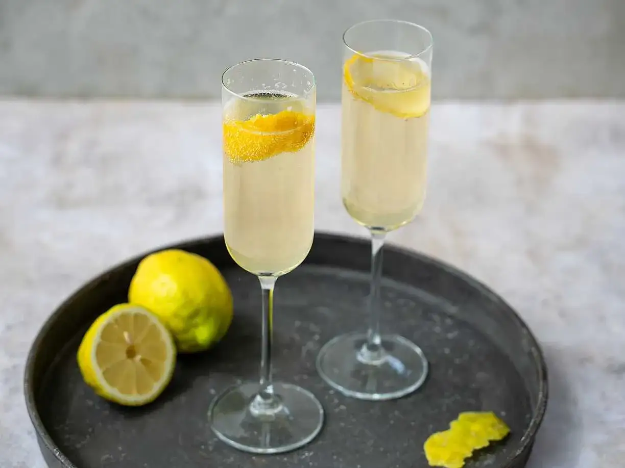 Två glas med bubblig dryck, garnerade med citronskal. En perfekt start för att lära sig hur dricker man limoncello.
