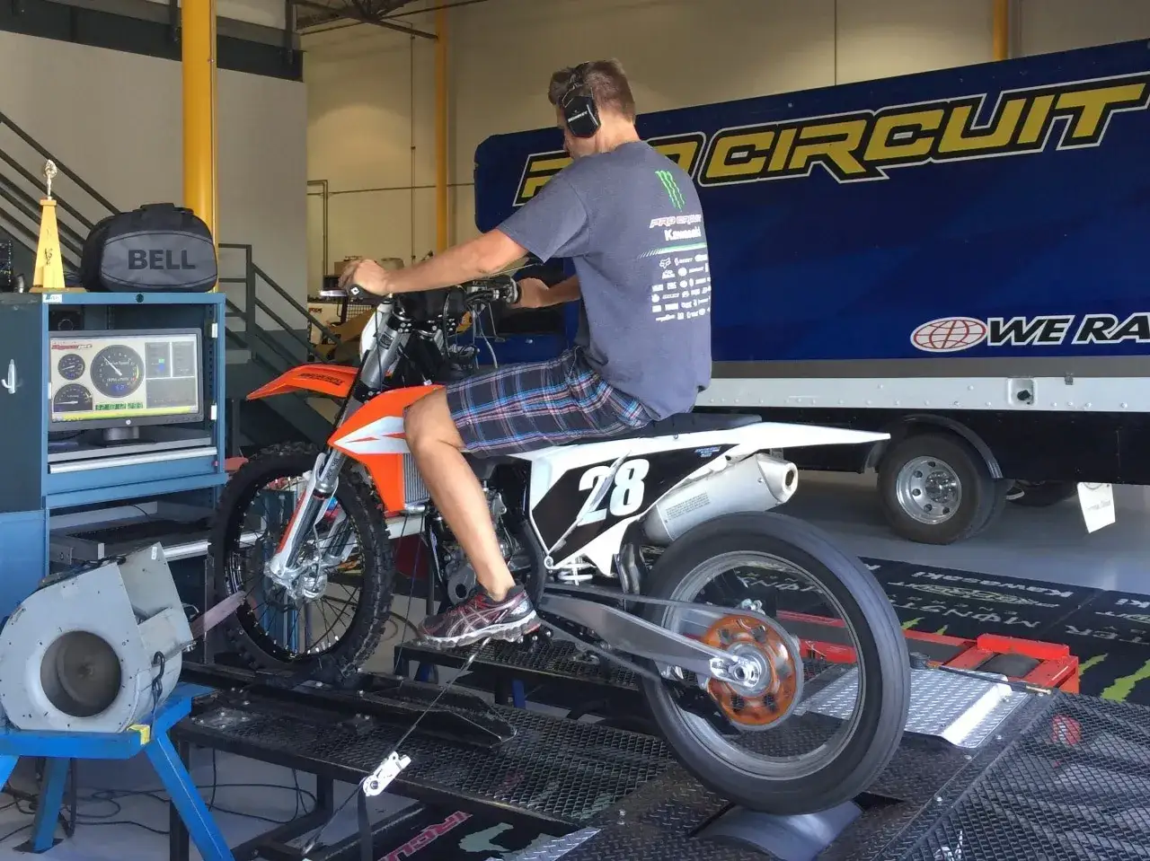 Un pilota su una moto da cross arancione è su un banco prova, pronto a scoprire come si misurano i cavalli di un motore.