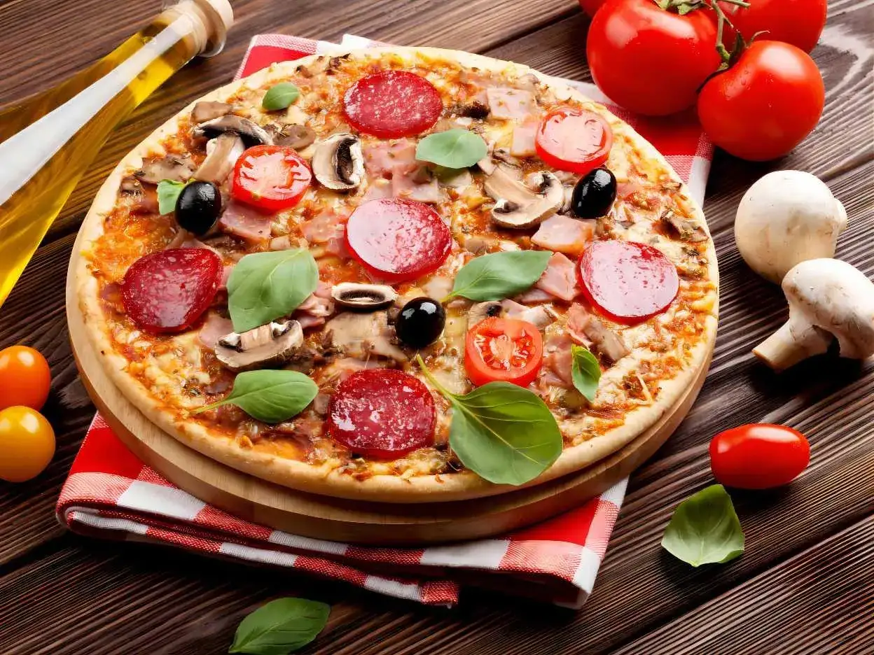 Une délicieuse pizza reine garnie de salami, champignons, olives et basilic, prête à être dégustée.