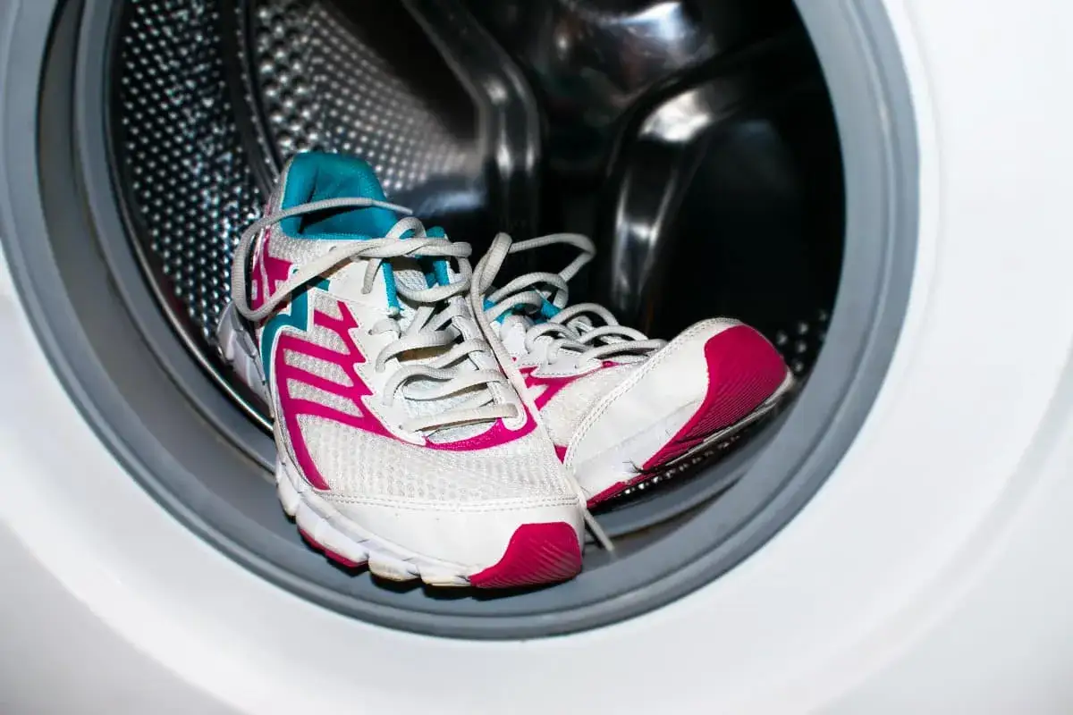 Zapatillas deportivas blancas con detalles fucsia y turquesa listas para lavar. ¿A qué temperatura lavar zapatillas? Frío o 30°C es ideal.