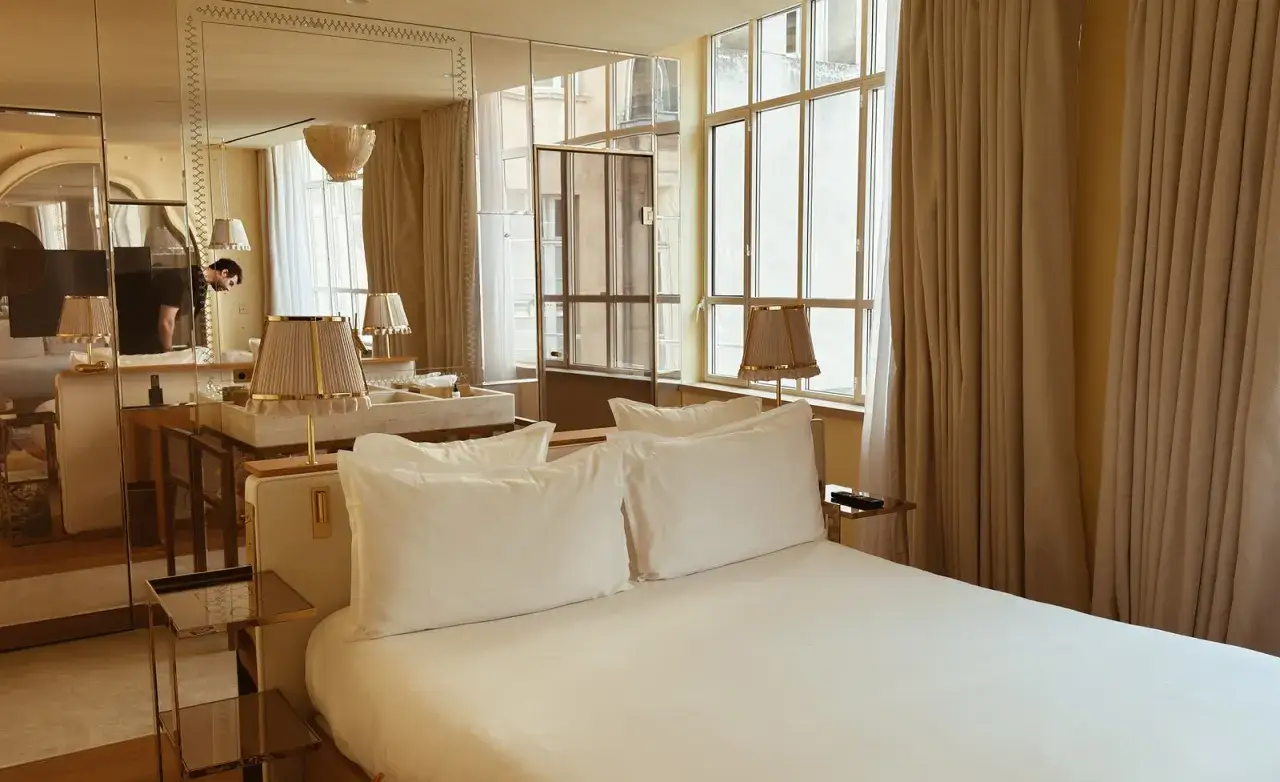 Ett lyxigt hotellrum med en stor säng, spegelvägg och stora fönster. Kanske ett rum som Sandra Beijer blogg skulle visa upp.